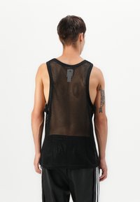 Top negru din plasă, cu design fără mâneci, având un decolteu rotund și spate deschis. Textura este respirabilă, potrivită pentru îmbrăcăminte sport.