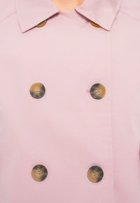 Ροζ διπλόσφιγγος παλτό με δομημένο γιακά, που διαθέτει στρογγυλά, καφέ κουμπιά και λεία υφή υφάσματος.