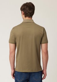 Olivově zelené polo tričko s jemnou texturou, krátkými rukávy a klasickým límcem. Má rovný lem a minimální detaily.
