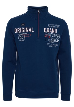 Navy blue pullover with a high collar and half-zip. Features various text prints in white and red, ribbed cuffs, and a logo patch on the arm.