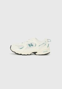 Zapatilla deportiva blanca con material de malla y sintético, con una suela negra, acentos en color verde azulado y un prominente logo "N" en el lateral.