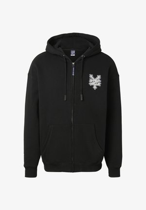 Sort hættejakke med lynlås, forlommer, snor til hætten og hvidt abstrakt emblem på venstre brystområde.