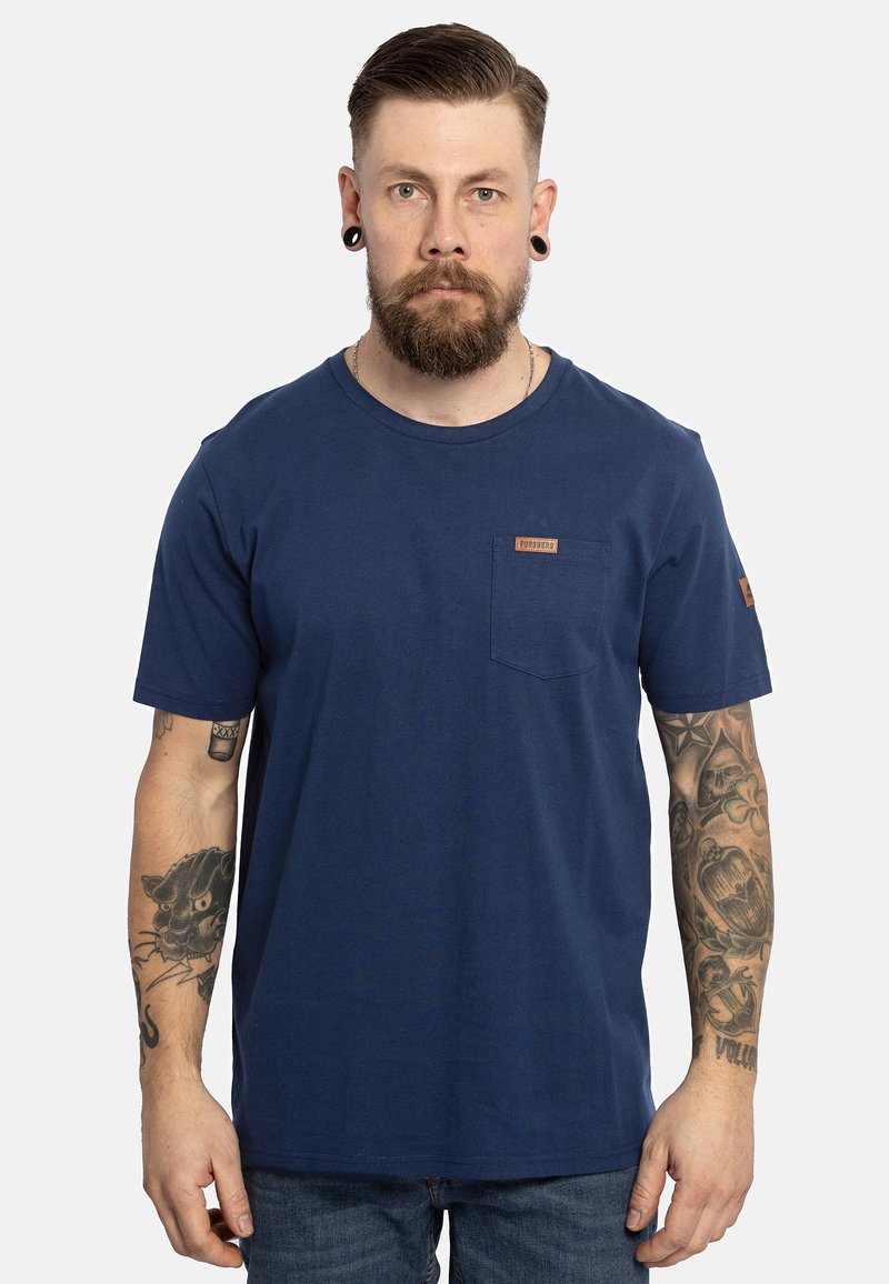 T-shirt in cotone blu navy con collo rotondo, maniche corte, taschino frontale e una patch in pelle con logo sul petto. Tessuto testurizzato.
