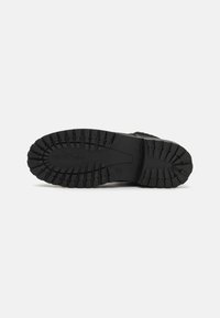 Suola di scarpe da trekking nera, caratterizzata da un pattern di battistrada robusto per aderenza e durata. Realizzata in gomma con una finitura texturizzata.