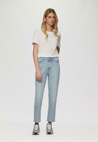 Biała koszulka z krótkim rękawem połączona z jasnoniebieskimi spodniami typu straight-leg i srebrnymi sneakersi, charakteryzująca się luźnym krojem i prostym wzornictwem.