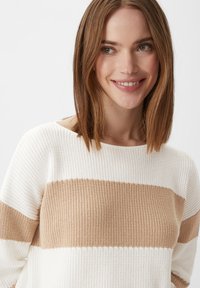 Sweter dzianinowy w kremowo-beżowe paski z szerokim dekoltem i teksturowaną powierzchnią, z poziomymi blokami kolorów.