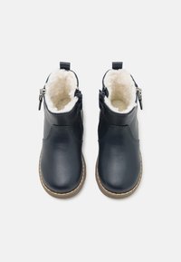 Botas de tobillo de piel de marino con forro de piel sintética, cremallera lateral, punta redonda y costuras en contraste a lo largo de la suela. Suela de goma plana y texturizada.