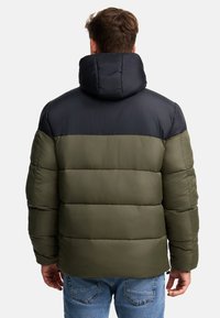 Puff jakke i mørkegrøn og sort, med vandret quiltning, fastgjort hætte og en glat, blank overflade.