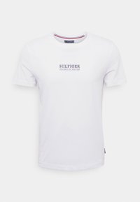 Valkoinen lyhythihainen crew neck -t-paita, jossa on sininen "HILFIGER COLUMBUS AVE. NEW YORK" -teksti painettuna rintaan.