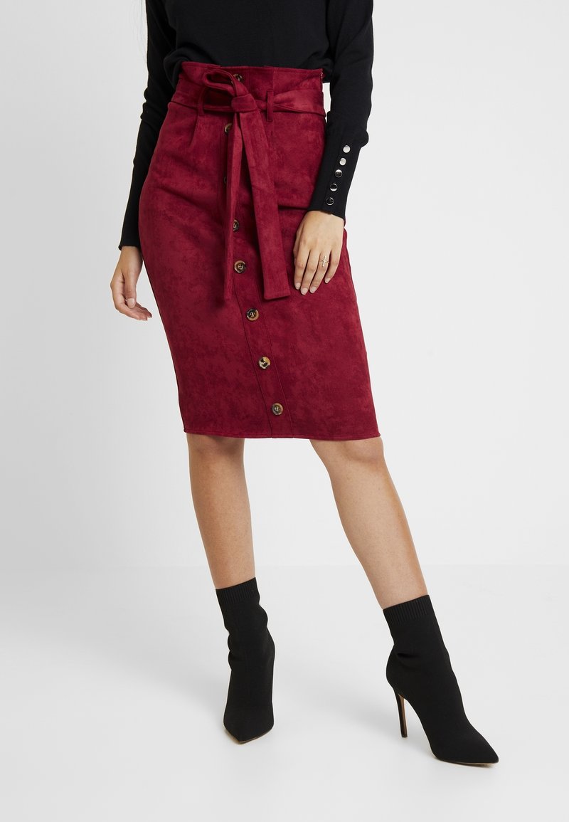 Burgundy mockask midi kjol med hög midja, knytdetalj, knappstängning framtill och synliga sömmar, kombinerad med svarta figursydda ankelstövlar.