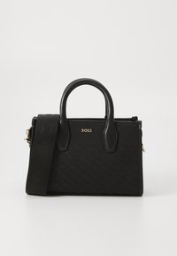 Black handbag featuring a textured fabric, gold hardware, dual handles, and a detachable strap, showcasing a minimalist design.