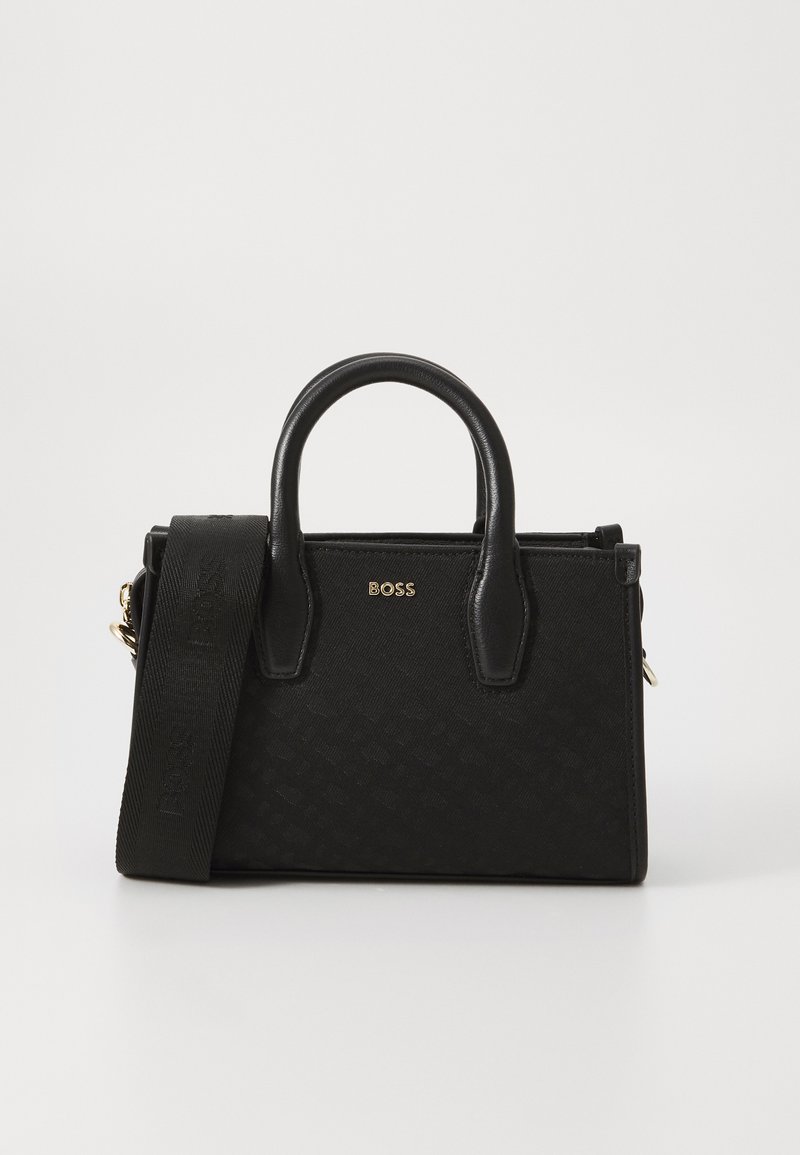 Black handbag featuring a textured fabric, gold hardware, dual handles, and a detachable strap, showcasing a minimalist design.