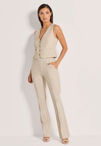 Beige maßgeschneiderte Weste mit tiefem V-Ausschnitt und Knopfschluss, kombiniert mit passenden, taillierten Hosen mit seitlichen Taschen und dezenten Nahtdetails.