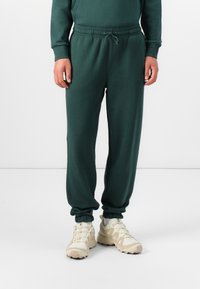 Grønne bomulds-joggers med elastisk talje og ankelsnor. Glat tekstur, minimalistisk design og funktionel snoretræk detalje.