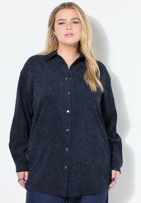 Camicia button-up blu navy realizzata in morbido corduroy, con colletto, maniche lunghe, due tasche sul petto e bottoni a pressione argentati.