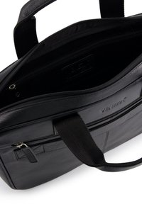 Sort lædertaske med lynlåslukning øverst, foret med stof, indvendige lommer og præget logo. Stærke håndtag til at bære i.