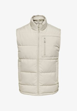 Chaleco acolchado beige con cuello alto, cremallera frontal y un bolsillo en el pecho con cremallera. Fabricado en un material sintético suave y ligero.