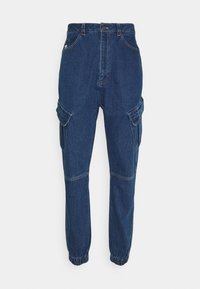 Pantalones cargo de denim azul con puños elásticos, múltiples bolsillos laterales y cintura alta. Presentan costuras en contraste y un cierre de botón.