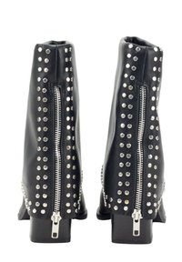 Botas de tobillo de piel sintética negra con acentos de tachuelas plateadas y cremalleras laterales. Los tacones cuadrados y una textura suave completan el diseño.