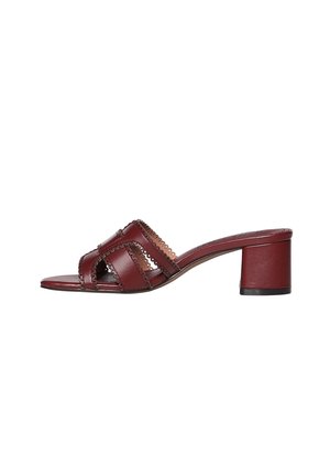 Sandale mule en cuir rouge à bout ouvert avec un talon bloc de hauteur moyenne et des détails festonnés sur les brides.