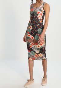 Dopasowana sukienka w kwiatowy wzór z czarnym tłem, kolorowymi motywami i cienkimi ramiączkami. Stylizowana w długości do kolan.