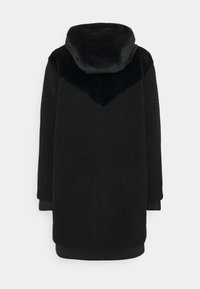 Cappotto teddy lungo nero con cappuccio e dettaglio in tessuto liscio a forma di V sulla parte superiore della schiena, mostrato di schiena su uno sfondo bianco.