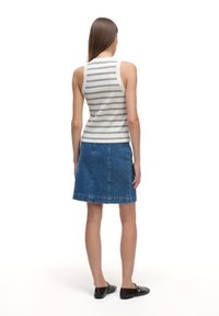 Pasiastrowany, dopasowany top na ramiączkach w biało-granatowe paski, zestawiony z niebieską dżinsową spódnicą w kształcie litery A z surowym brzegiem. Całość uzupełniają czarne, płaskie buty.
