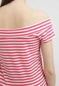 Top bez ramínek s růžovými a bílými vodorovnými pruhy. Vyroben z jemné látky s volným střihem a krátkými rukávy.