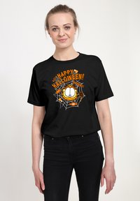 Sort t-shirt med et "Glædelig Halloween!" grafisk motiv, der inkluderer et design af en orange kat, slik og spindelvævsdetaljer. Kortærmet og med rund hals.