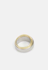 Anello in metallo argentato e dorato con una superficie liscia e lucida, caratterizzato da un accento prominente in oro giallo e marchiatura incisa all'interno.