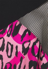 Tissu noir, panneau en mesh noir, et tissu à imprimé animalier rose vif et rose clair avec des taches noires irrégulières cousus ensemble.
