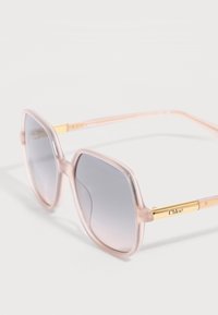 Gafas de sol cuadradas con montura translúcida de color rosa, lentes degradadas en gris y patillas en tono dorado grabadas con la marca "Chloé".