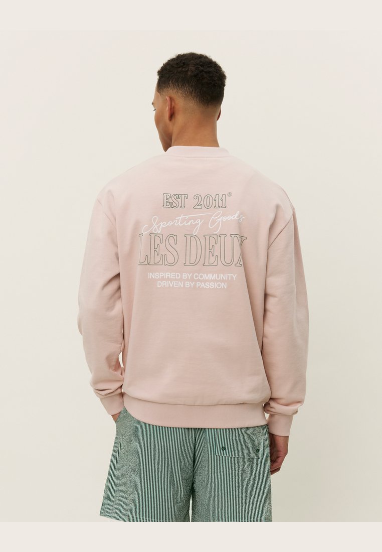Helle rosa Sweatshirt mit dem Text "EST 2011" und "LES DEUX" auf der Rückseite, Rundhalsausschnitt und gerippten Bündchen. Aus Baumwollmischung.