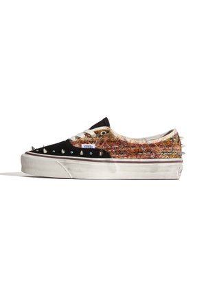 Zapatilla Vans de corte bajo con puntera negra, tejido peludo multicolor, cordones blancos, púas metálicas en los laterales y el talón, y suela de goma blanca.