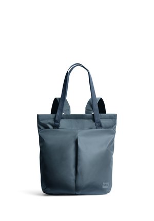 Borsa tote in tessuto morbido blu scuro con due manici lunghi e due tasche frontali, mostrata in posizione verticale su sfondo bianco.