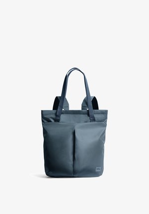 Borsa tote in tessuto morbido blu scuro con due manici lunghi e due tasche frontali, mostrata in posizione verticale su sfondo bianco.