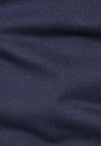 Gros plan d’un tissu tricoté bleu foncé montrant un tissage fin texturé et des plis doux.