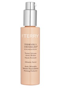 Terrybly Densiliss Foundation in einer zylindrischen Glasflasche, hellpeachfarbe, silberner Pumpspender, mit schwarzer Schrift auf der Vorderseite.