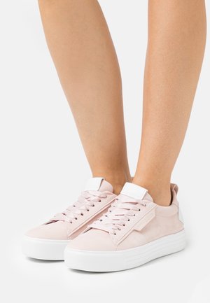 Vaaleanpunaiset lenkkitossut, joissa on sileä pinta, valkoiset nauhat ja valkoinen kieli. Paksu valkoinen kumipohja ja hillityt sivukoristeet.