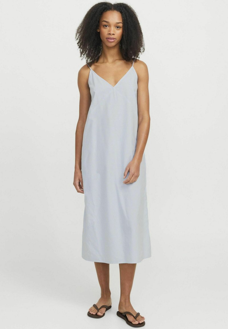 Vestido midi de rayas azul claro con tirantes finos, escote en V, tejido fluido y una silueta relajada. Llevado con chanclas marrones.