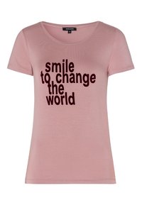 Camiseta de manga corta de color rosa claro con escote redondo que presenta un texto en negrita negro: "sonríe para cambiar el mundo". Tela suave con una textura lisa.