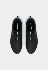 Ζεύγος μαύρων παπουτσιών για τρέξιμο Nike με λευκές σόλες, γκρι λογότυπα swoosh, κορδόνια και θηλιές, τοποθετημένα δίπλα-δίπλα σε λευκό φόντο.