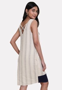 Beige ärmelloses Kleid mit vertikalen marineblauen Streifen, V-förmigem Rückendesign, seitlichen Schlitzen und einem einfarbigen marineblauen Saum am Boden.