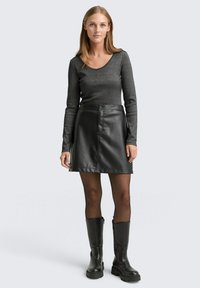 Szara bluzka z długimi rękawami i okrągłym dekoltem, dopasowana do czarnej spódnicy w kształcie litery A z eco-skóry. Całość dopełniają czarne kozaki do kolan.