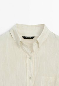 Chemise en lin à col blanc avec boutons sur le devant et une poche poitrine, étiquetée Massimo Dutti, fabriquée au Portugal.