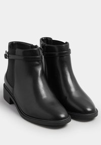 Svarta ankelskor i smidig läder med en låg klack, med en sidodragkedja och ett tunt band runt vristen.