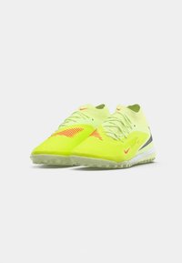 Zapatillas deportivas de corte bajo en amarillo neón con franjas de acento rojas, entresuelas blancas y suelas exteriores grises texturizadas, dispuestas lado a lado sobre un fondo blanco.