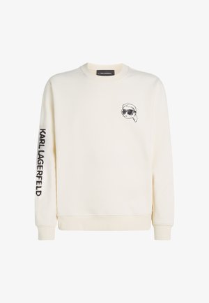 Kreemi värvi crewneck dressipluus. Ees on väike must graafika, kus on prillidega nägu, ja hiirekulul on tekst "KARL LAGERFELD".