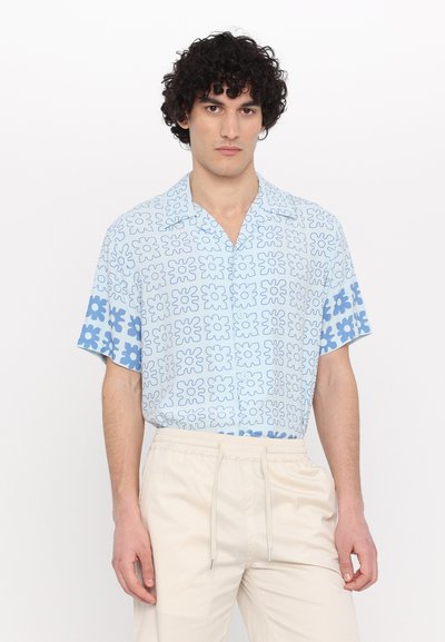 Cămașă cu mânecă scurtă în albastru deschis, cu un model geometric de flori. Guler cu butoni, croi lejer, complementar cu pantaloni bej cu talie elastică.