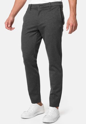 Charcoal-graue Hose aus weichem Stoff, taillierte Passform mit flachem Front, Seitentaschen und standardmäßiger Knopfverschluss. Getragen mit weißen Sneakers.